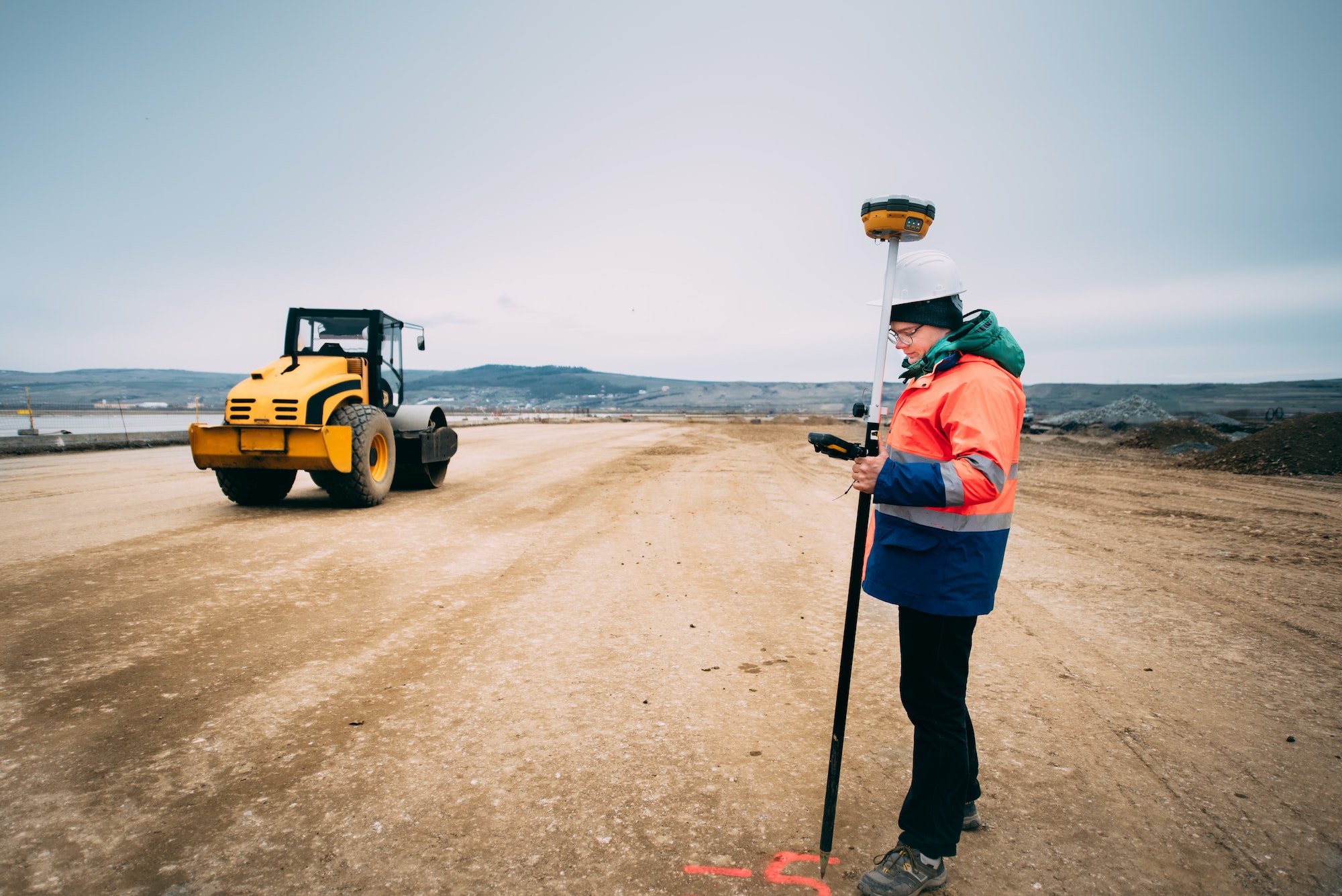 Portrait of engineer on construction site, surveyor using gps system